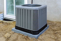 A condenser installed on a raised platform, on level ground, with no obstructions