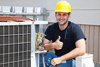 Monmouth County air conditioner repair technician wearing yellow hard hat giving thumbs up while fixing an outdoor condenser